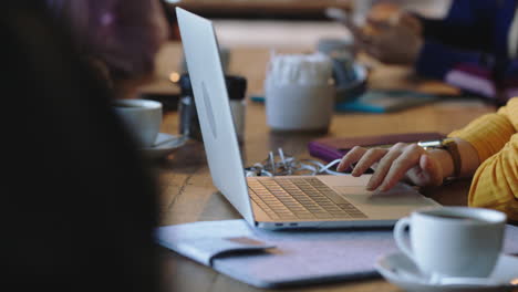 close up hands young woman student using laptop in cafe drinking coffee browsing online reading messages enjoying study relaxing busy restaurant