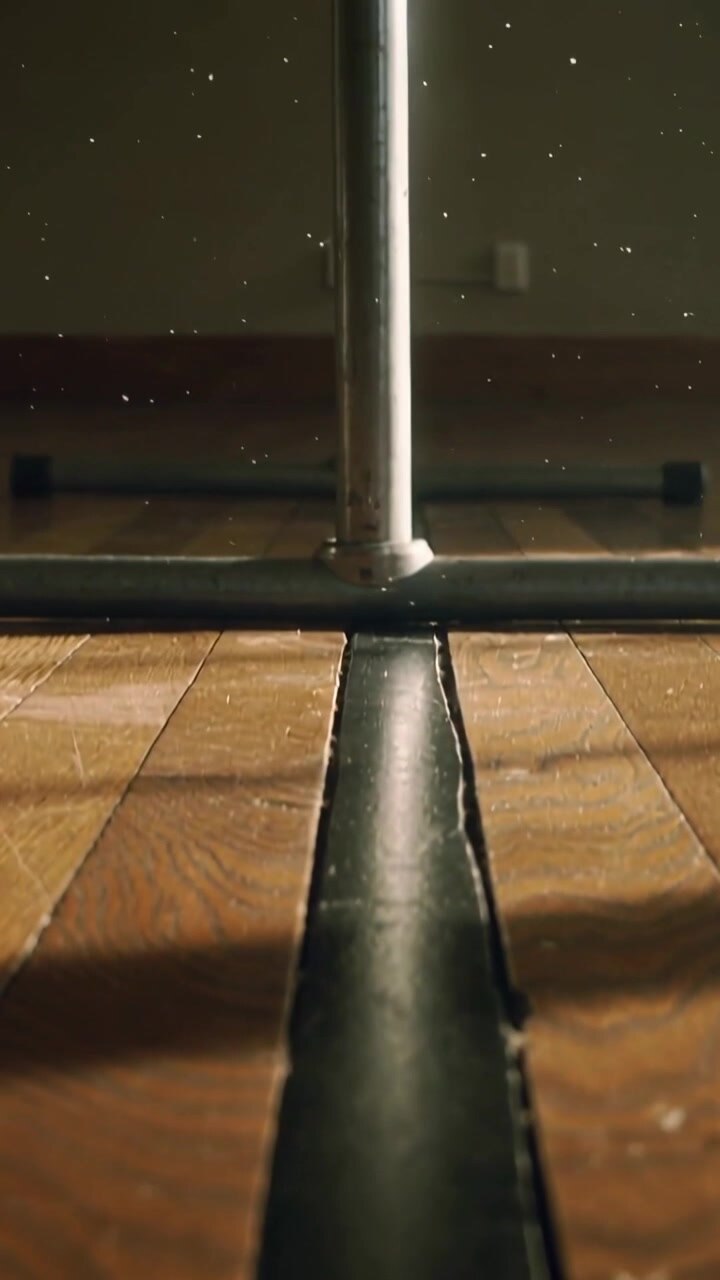Video verticale: La telecamera si allontana, una linea nera attraversa il pavimento fino alla sbarra in uno studio, pulviscolo.