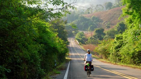 back view of women riding cycle in the road of pak nai fisherman village, nan province, thailand