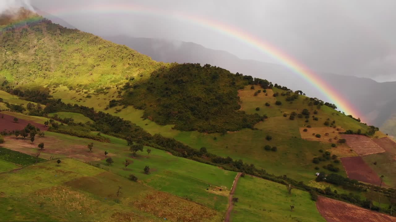 vista aérea del hermoso arco iris multicolor en el cielo sobre las montañas y los campos verdes en ecuador