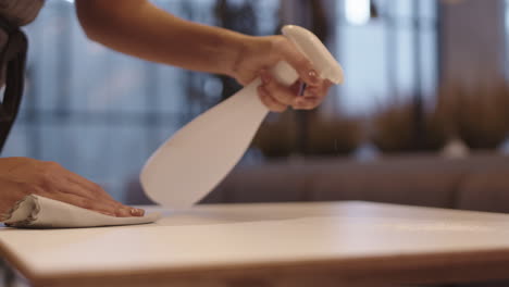 unrecognizable person disinfecting table