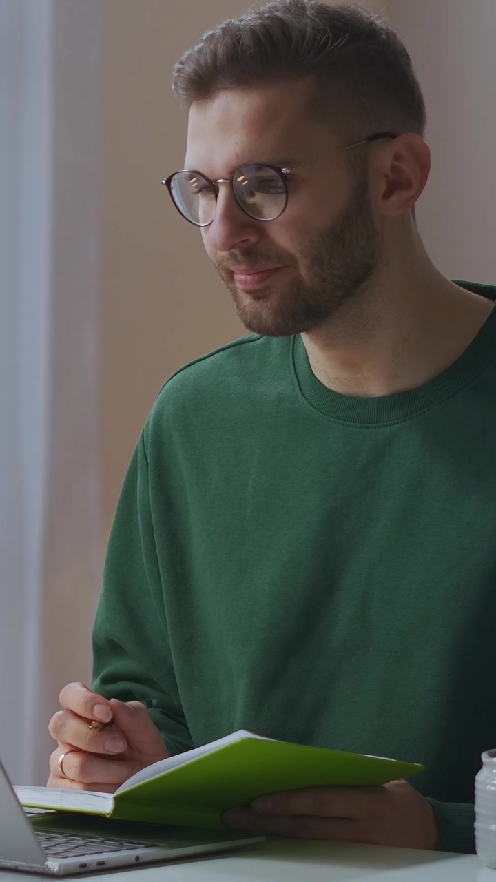 Fokusert ung mann skriver notater og ser på bærbar PC