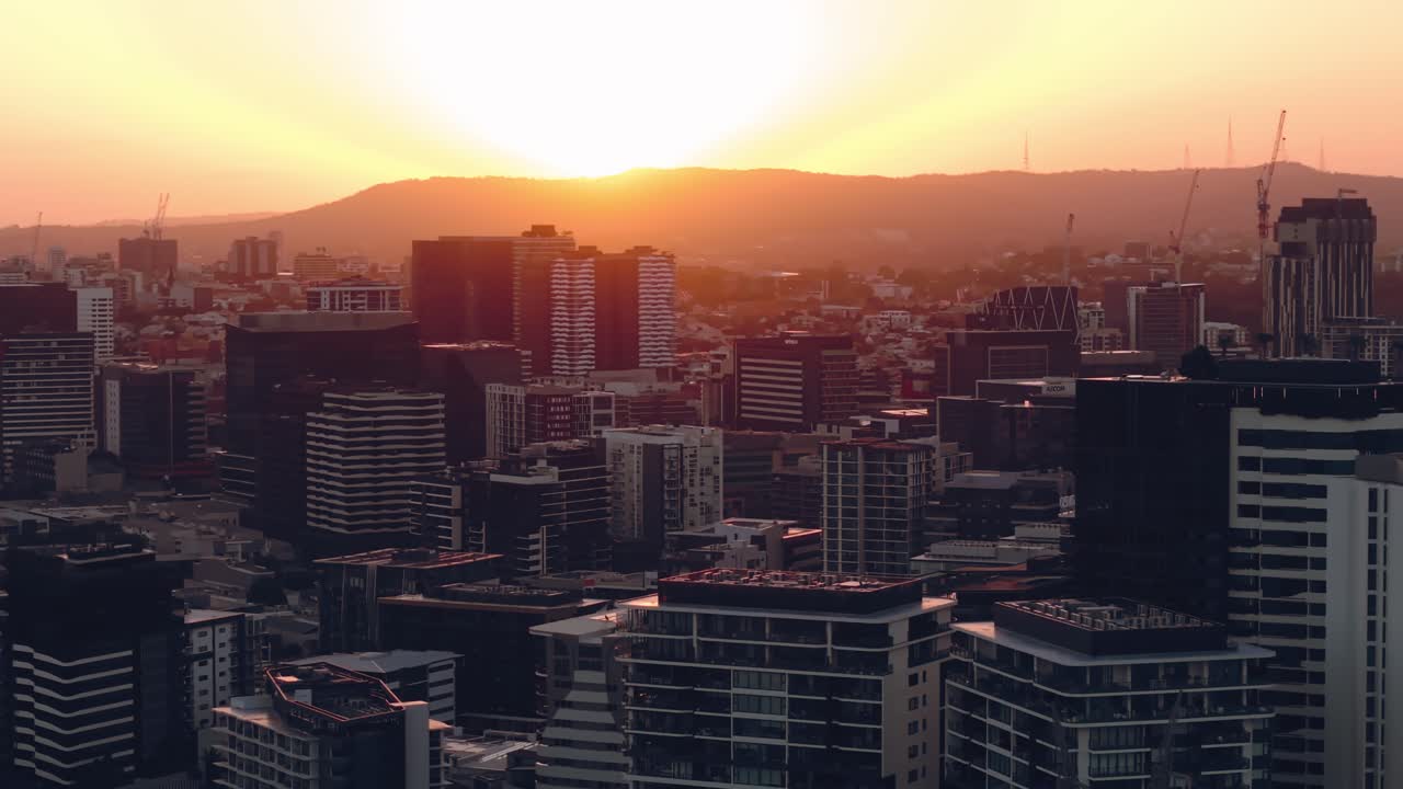 Vista aérea do subúrbio de Tenerife ao pôr do sol com luz quente iluminando o denso horizonte urbano, estabelecendo um plano de fundo médio
