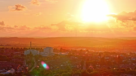 static drone shot of barnsley skyline at sunset with barnsley hospital in the foreground and the tall emley moor tv transmitter silhouetted on the horizon, warm golden tones cast across rooftops,