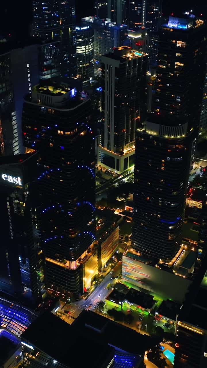 Drone slowly descending above the skyscrapers in the downtown of Miami, Florida, USA. City lights from top. Vertical video