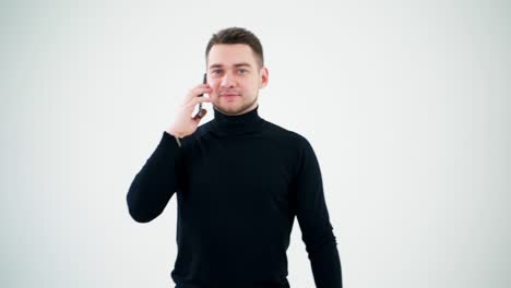 professional creative man talking on the smartphone. handsome man in black sweater using mobile phone isolated on white studio background.