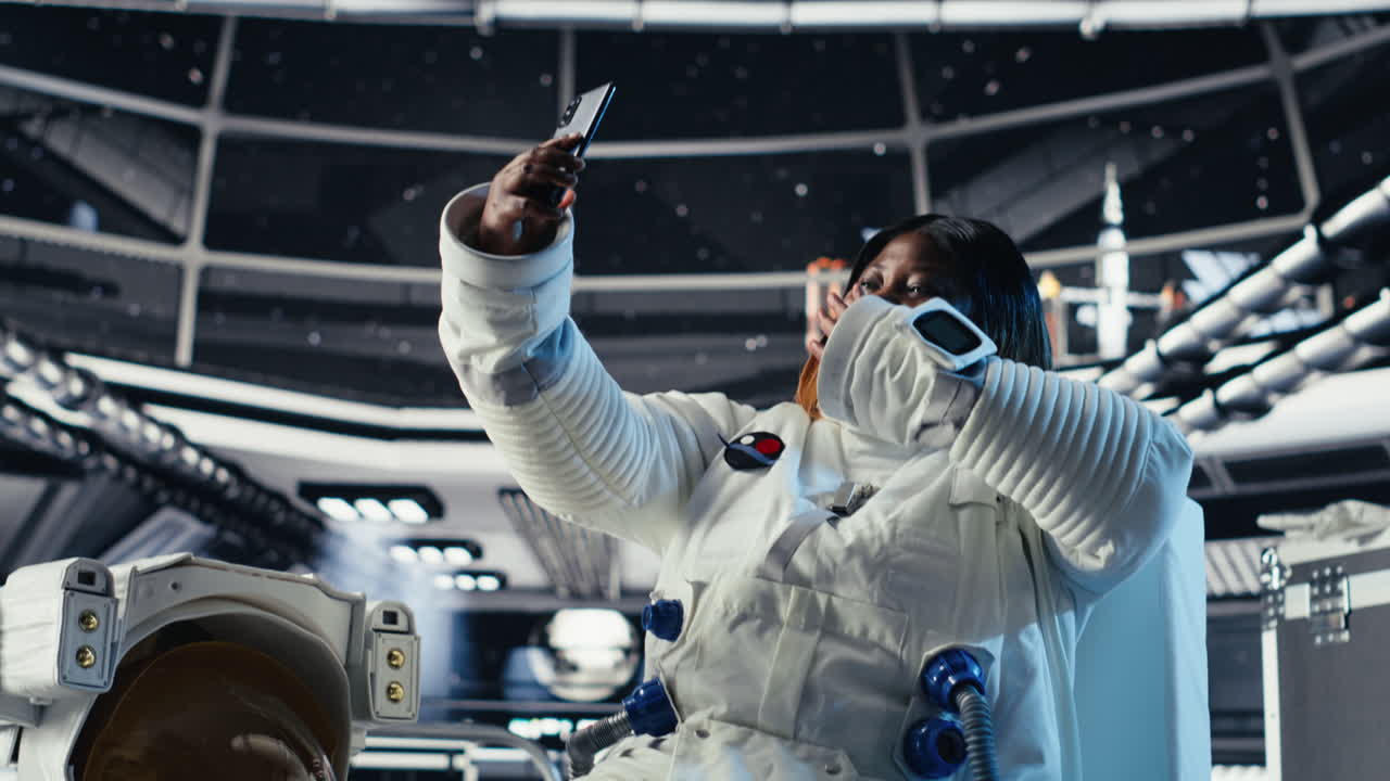 Jolly astronaut having fun in starship doing selfies using smartphone camera