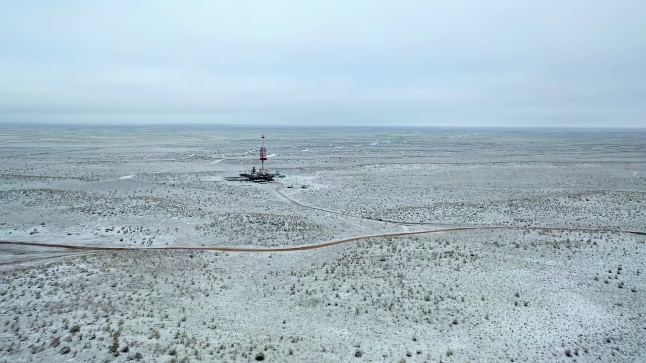 Veduta aerea di un impianto di trivellazione per petrolio e gas in un paesaggio desertico ghiacciato durante l'inverno.