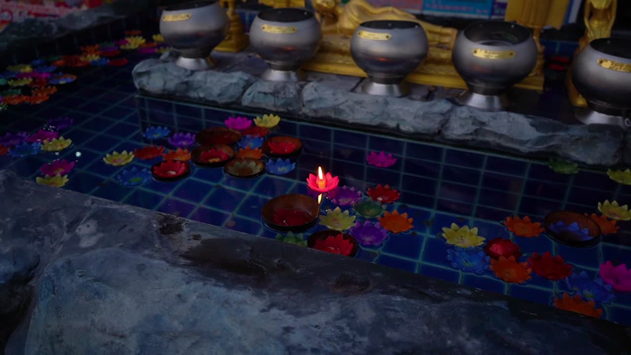 Prayer flower shape candles floating in a water fountain Wat Rong Sear Tean (Blue Temple). Chiang Rai, Thailand.