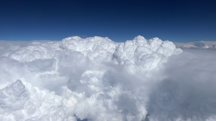 Large white cumulonimbus clouds on a sunny day seen from a pilot in an airplane