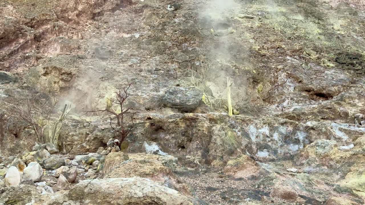Barren volcanic landscape with sulfur deposits and fumaroles producing hot steam in an active geothermal zone