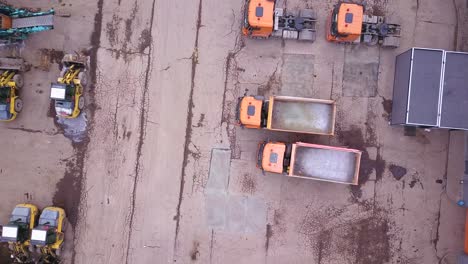 aerial shot of bulldozer and trucks in outside warehouse