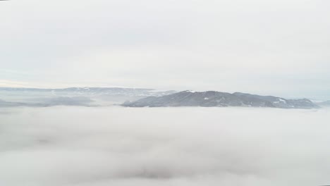 panning shot of a winter landscape above the fog line