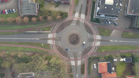 top down aerial of cars entering and leaving roundabout - slow lift up