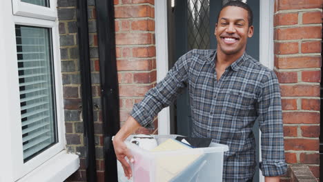 Portrait-Of-Male-College-Student-Carrying-Box-Moving-Into-Accommodation