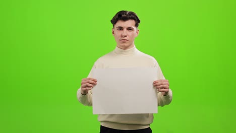 el hombre está de pie y mirando a la cámara. tiene un papel blanco. está de pie sobre un fondo verde. pantalla verde. 4k.