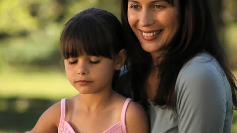 mamá y hija soplando burbujas sentadas en el césped