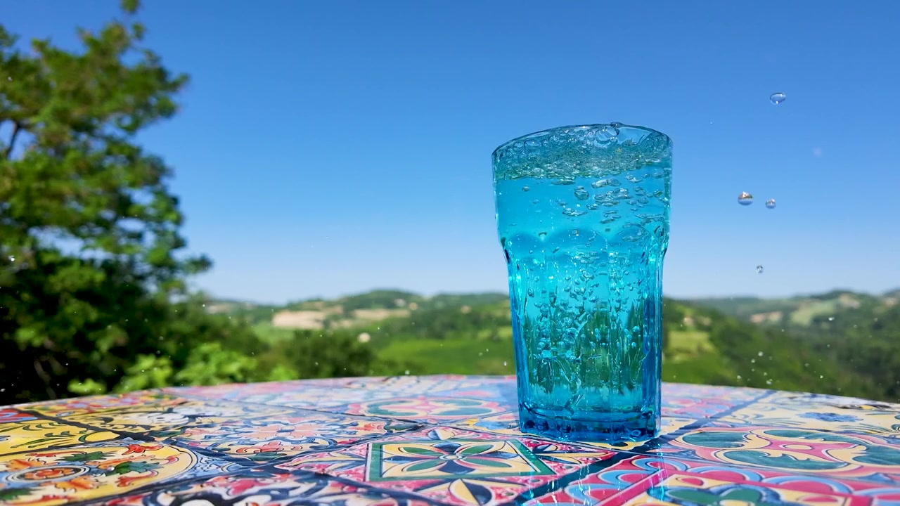 Bevanda blu frizzante in un bicchiere su un tavolo a mosaico colorato