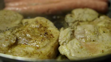 Close-up-view-of-some-frying-smelt-cutlets-and-chicken-sausages-in-the-background-in-the-kitchen