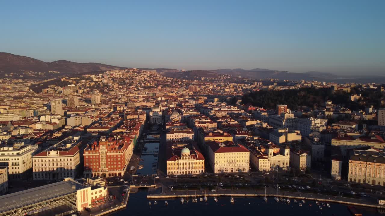 Aerial drone footage captures the warm colors of sunset over the coastal city of Trieste in Italy