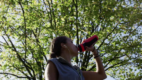 Runner woman drinking water bottle sun flare solar energy