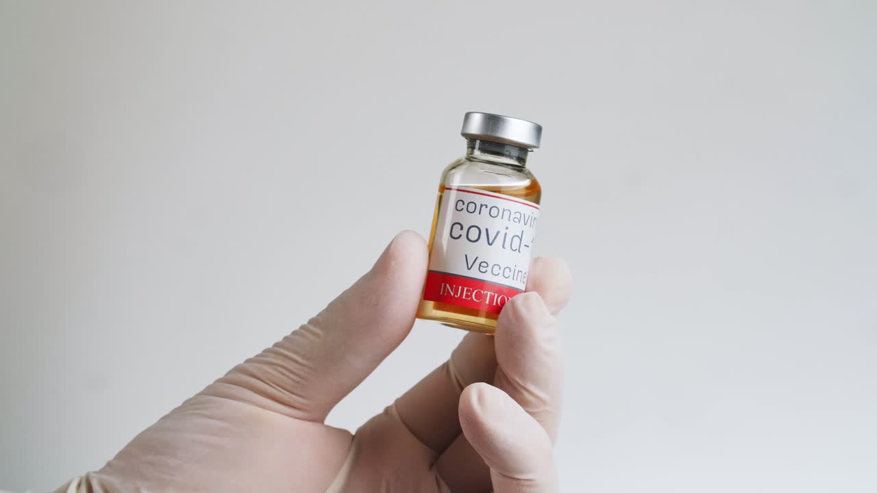 vial de vacuna contra la covid-19 en mano con guantes
