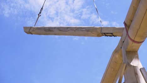 crane lifting large wooden beam for timber framing project