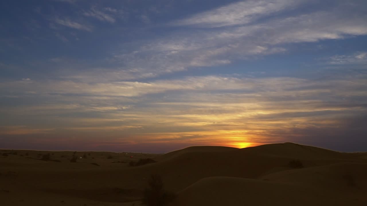 Sunset with blue skies and clouds over desert sands