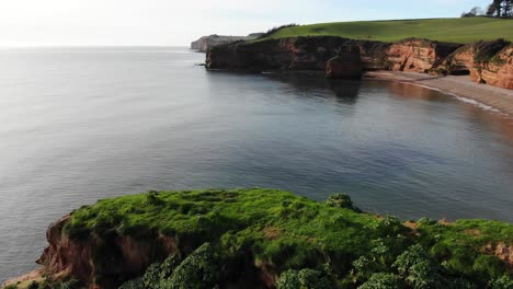 Stunning-Ladram-Bay---camera-glides-slowly-over-cliffs,-revealing-breathtaking-views-of-the-rocky-shores-and-serene-waters-below