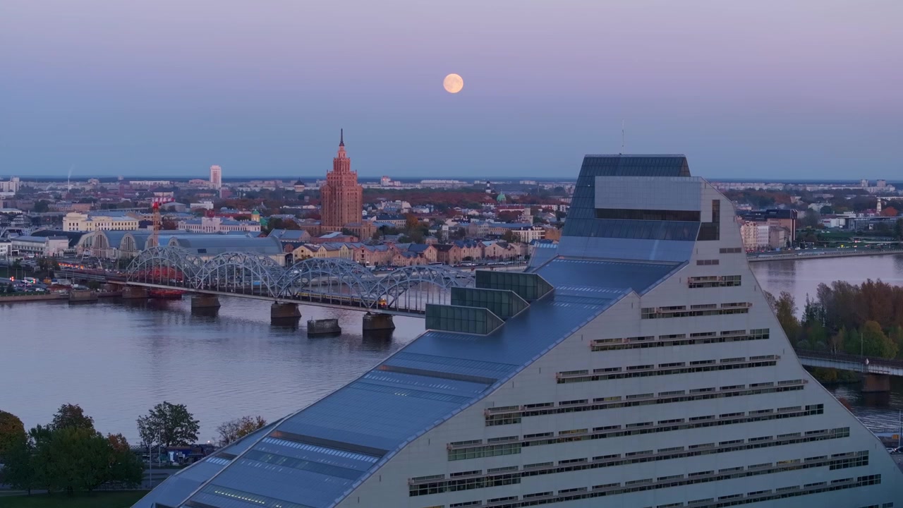 Tramonto sulla Biblioteca Nazionale della Lettonia, con un drone che cattura la luna piena