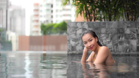 traje de baño modelo asiático de moda posando en una piscina