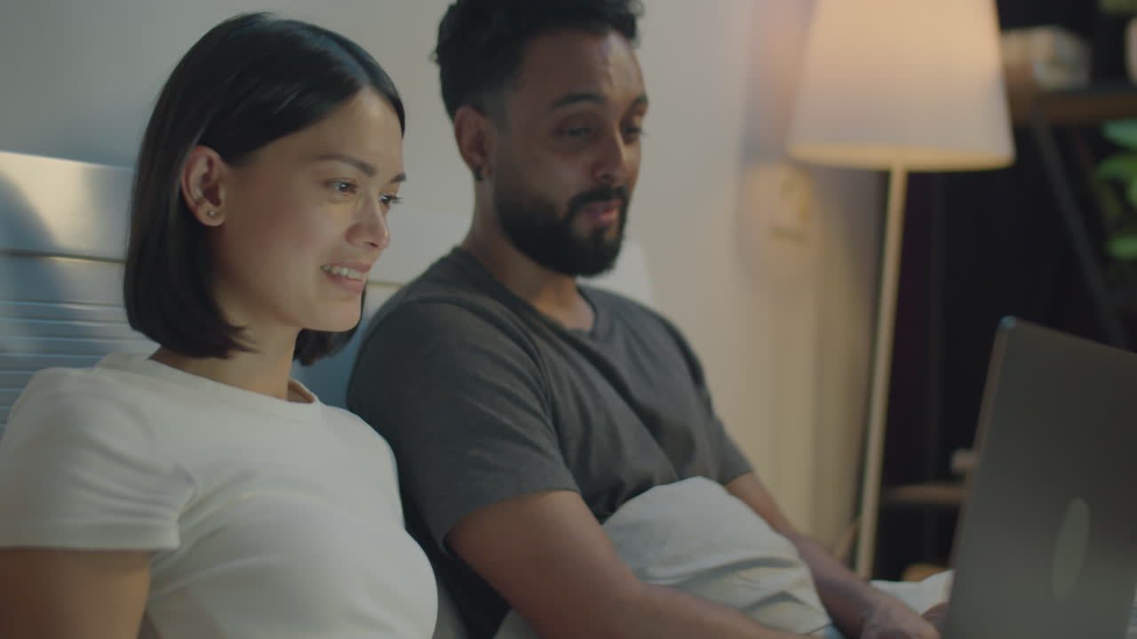 침대에서 노트북에서 영화를 보는 커플