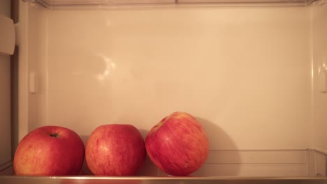 healthy eating, food and diet concept - dark haired young man opening fridge at home kitchen, drinking and putting back black sports bottle on fridge shelf and leaving