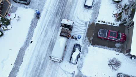 overhead aerial view of a garbage truck picking up trash in snow conditions