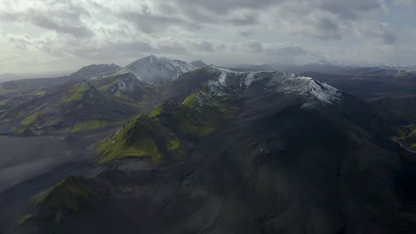 Un-Video-De-Drones-En-Cámara-Lenta-De-Las-Tierras-Altas-Del-Sur-De-Islandia-Que-Muestra-Arenas-Negras,-Musgo-Verde-Y-Nieve-En-Las-Montañas
