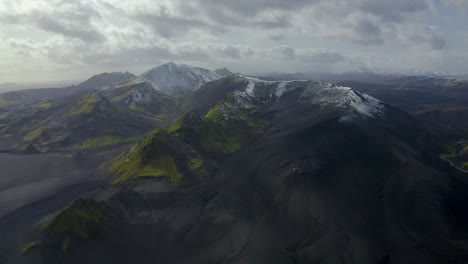 A-slow-motion-drone-video-from-the-Highlands-of-South-Iceland-showing-black-sands,-green-moss-and-snow-in-the-mountains