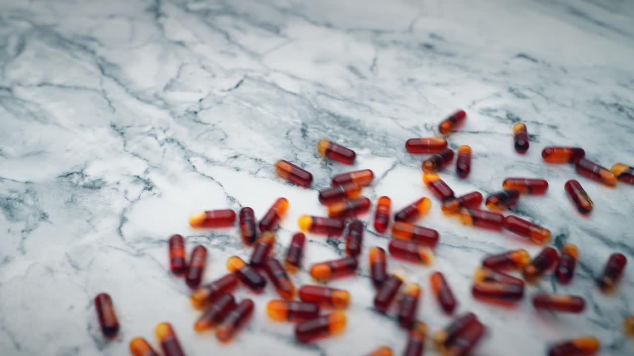 cápsulas de aceite de krill rojo que se vierten sobre una mesa de mármol blanco
