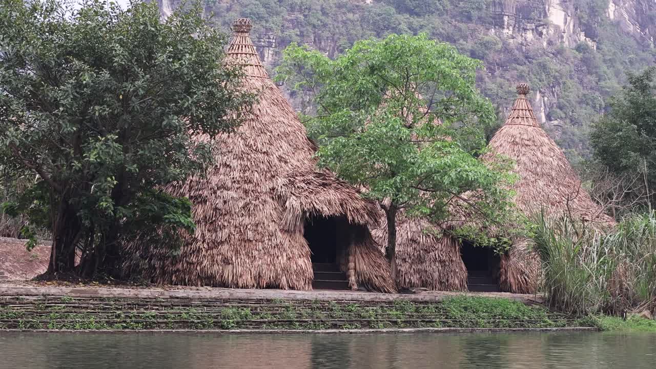 cabañas de paja junto a un río con luces y sombras cambiantes.