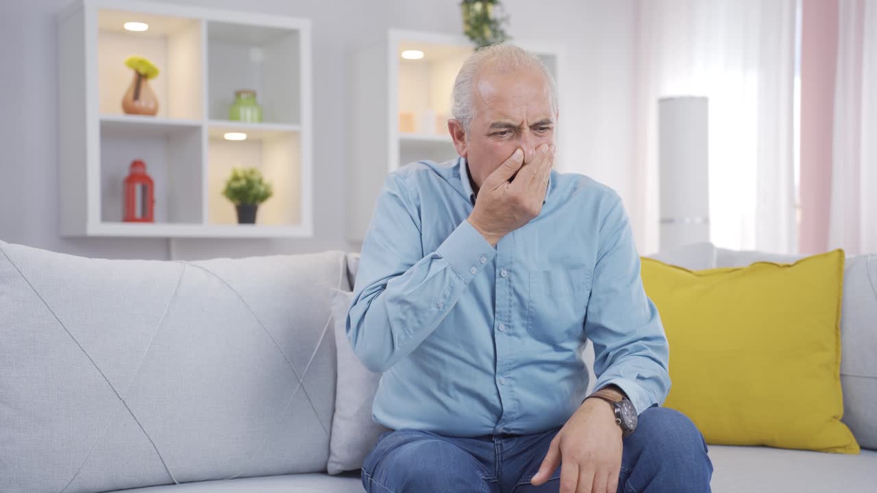 The old man who smells bad odor is disturbed and disgusted.