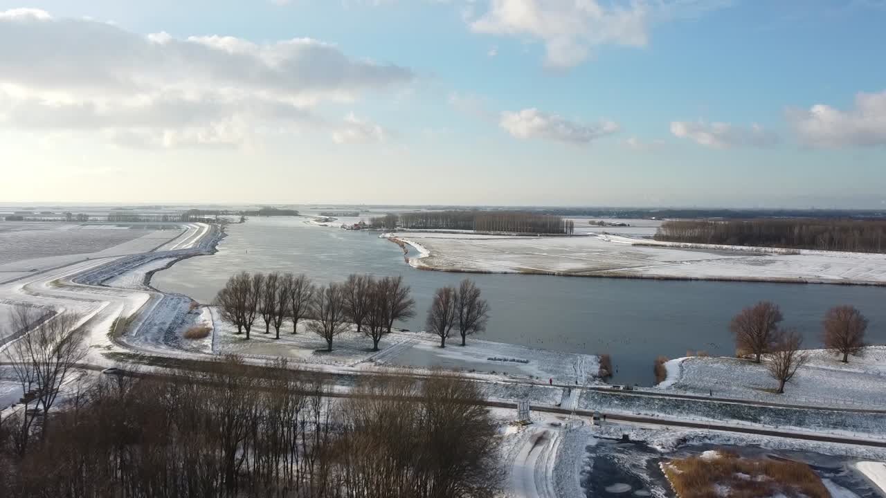 Flying towards a river with a drone above a frozen ditch in a winter landscape