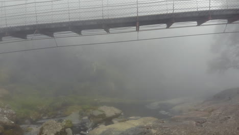 A-drone-shot-of-a-suspension-bridge-in-a-dense-fog-in-Sun-Link-Sea-National-Park,-Taiwan