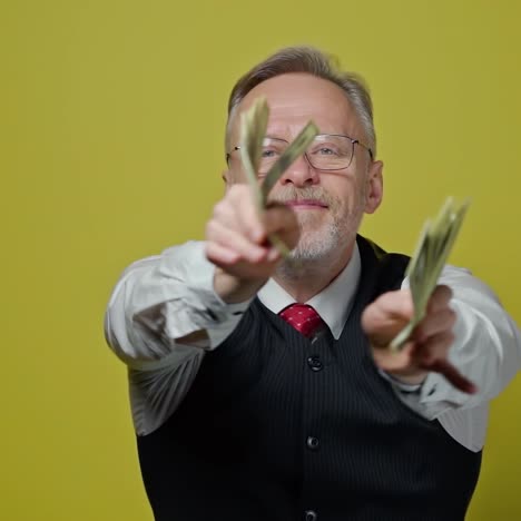 happy senior businesman waving dollar banknotes.rich grey-haired man holding big amount of money in his hands and showing them on the camera.