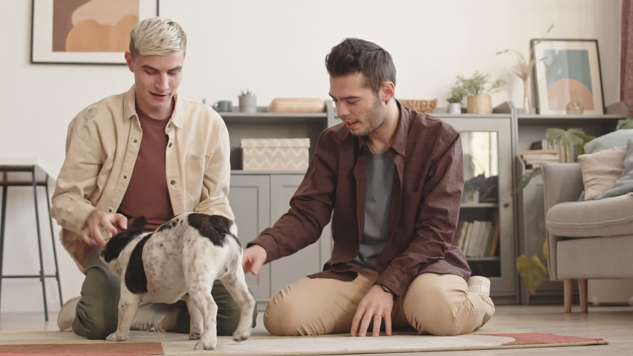 Two Young Men Playing with Dog at Home