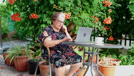 aged female speaking on phone at table with laptop