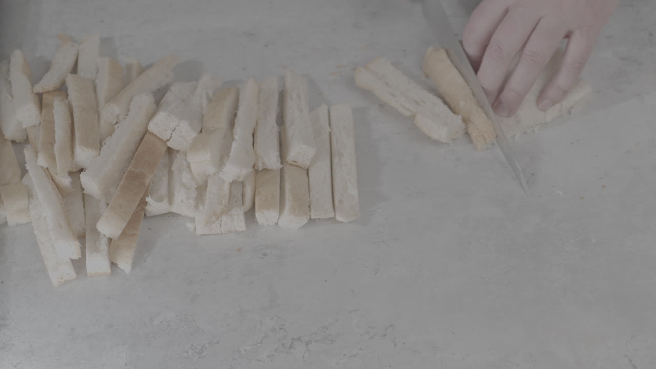 여러 조각의 빵에서 빵 껍질의 모든 면을 잘라내는 요리사의 클로즈업 샷