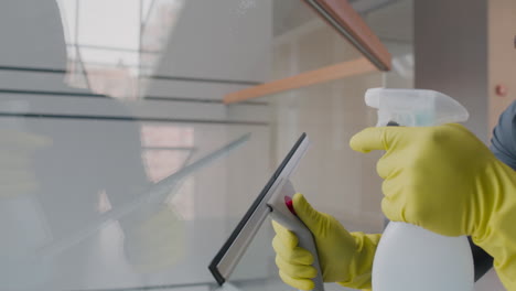 close up view of cleaning man hands wearing gloves cleaning stair railing and crystals inside an office building