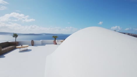 idílica terraza blanca con mesa y sillas, con vistas al volcán y al mar egeo