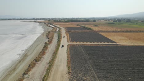 Aerial-view-behind-ATVs-driving-by-salt-lake,-Kos,-Greece