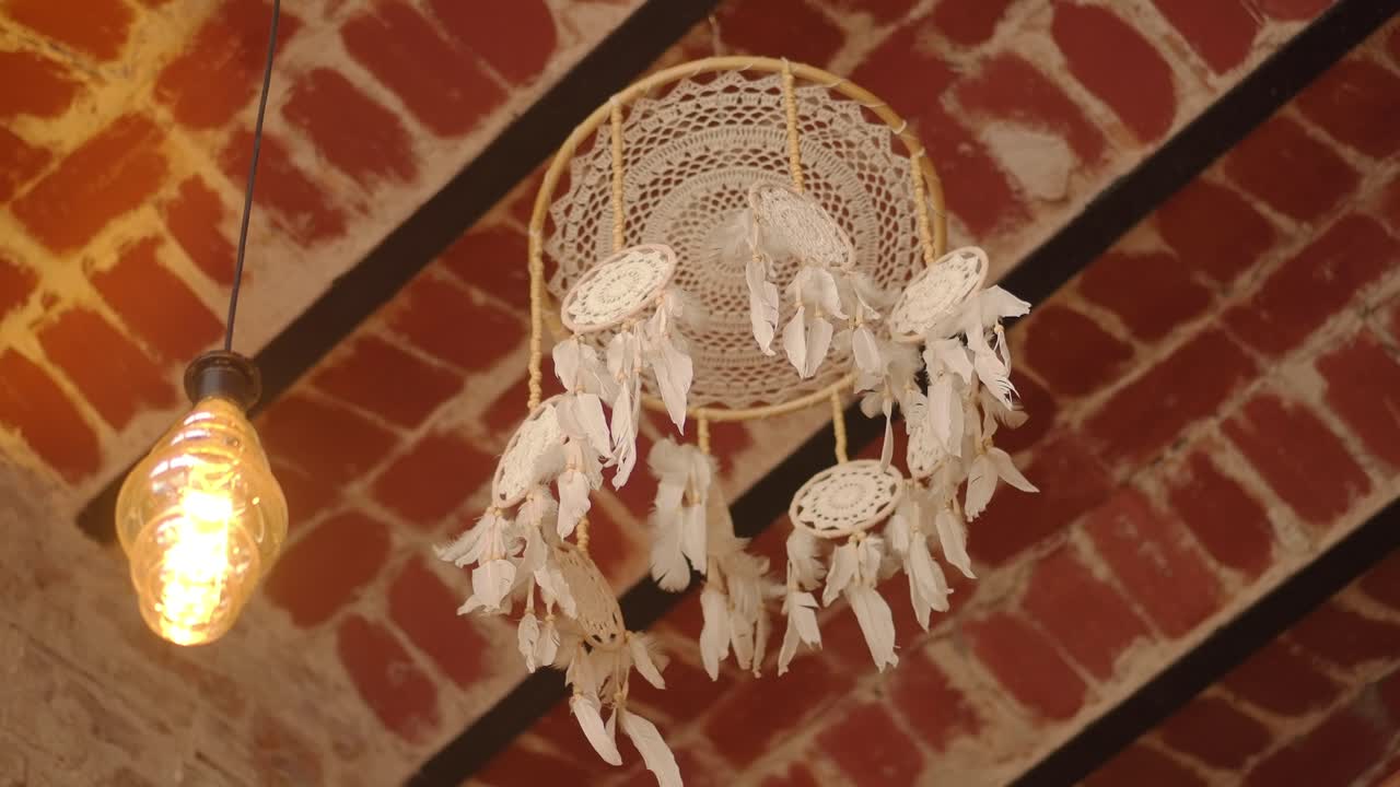 Acchiappasogni bohémien appeso a un soffitto rustico in mattoni con lampadina Edison