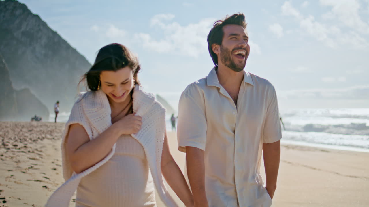 행복한 임신 가족이 아름다운 여름 해변을 고 손을 잡고 가까이 다니고 있습니다.